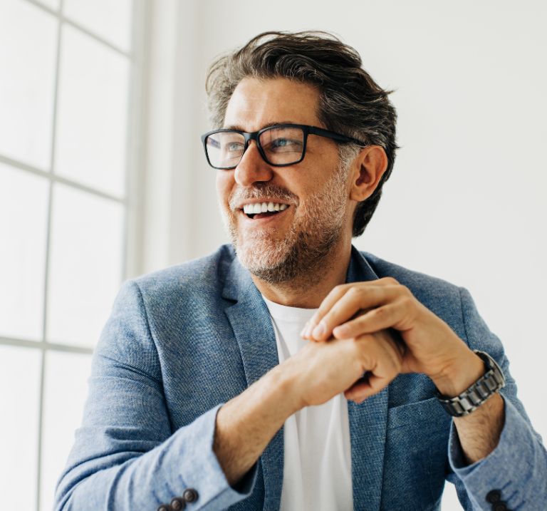 A man smiling with confidence—highlighting his bright white and straight teeth.