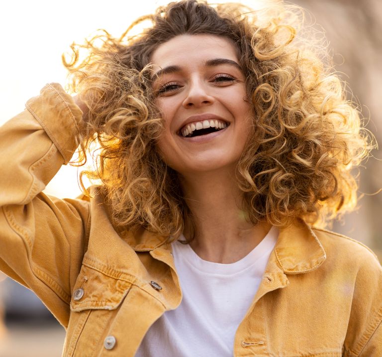A woman smiling confidently—highlighting the importance of quality dental care.